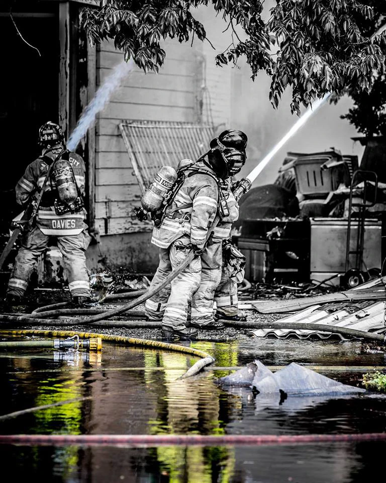 A dramatic photo of firefighters spraying water on a fire