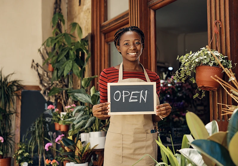 A flower shop owner with an open for business sign